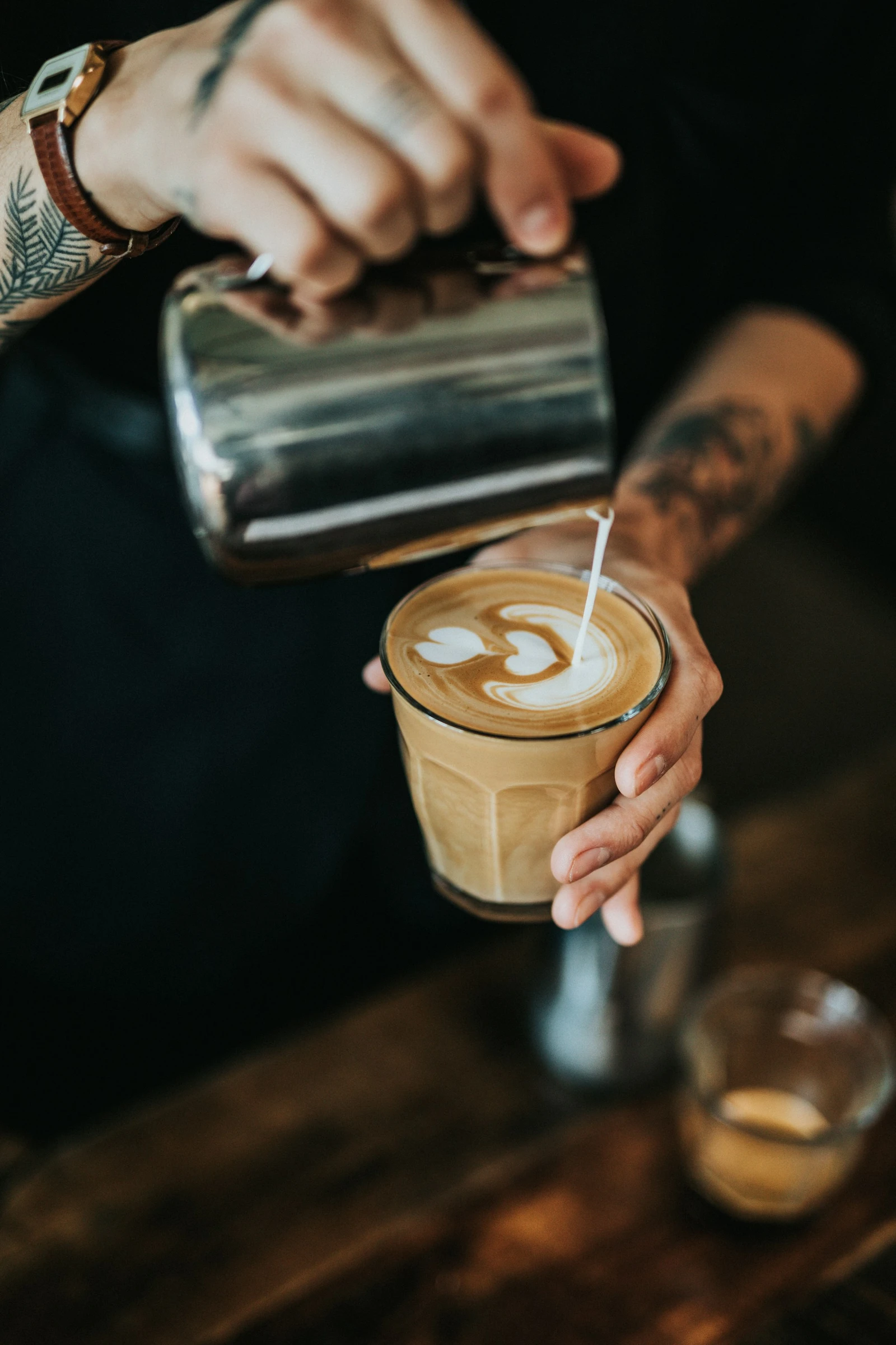 A barista pouring latte art into a glass